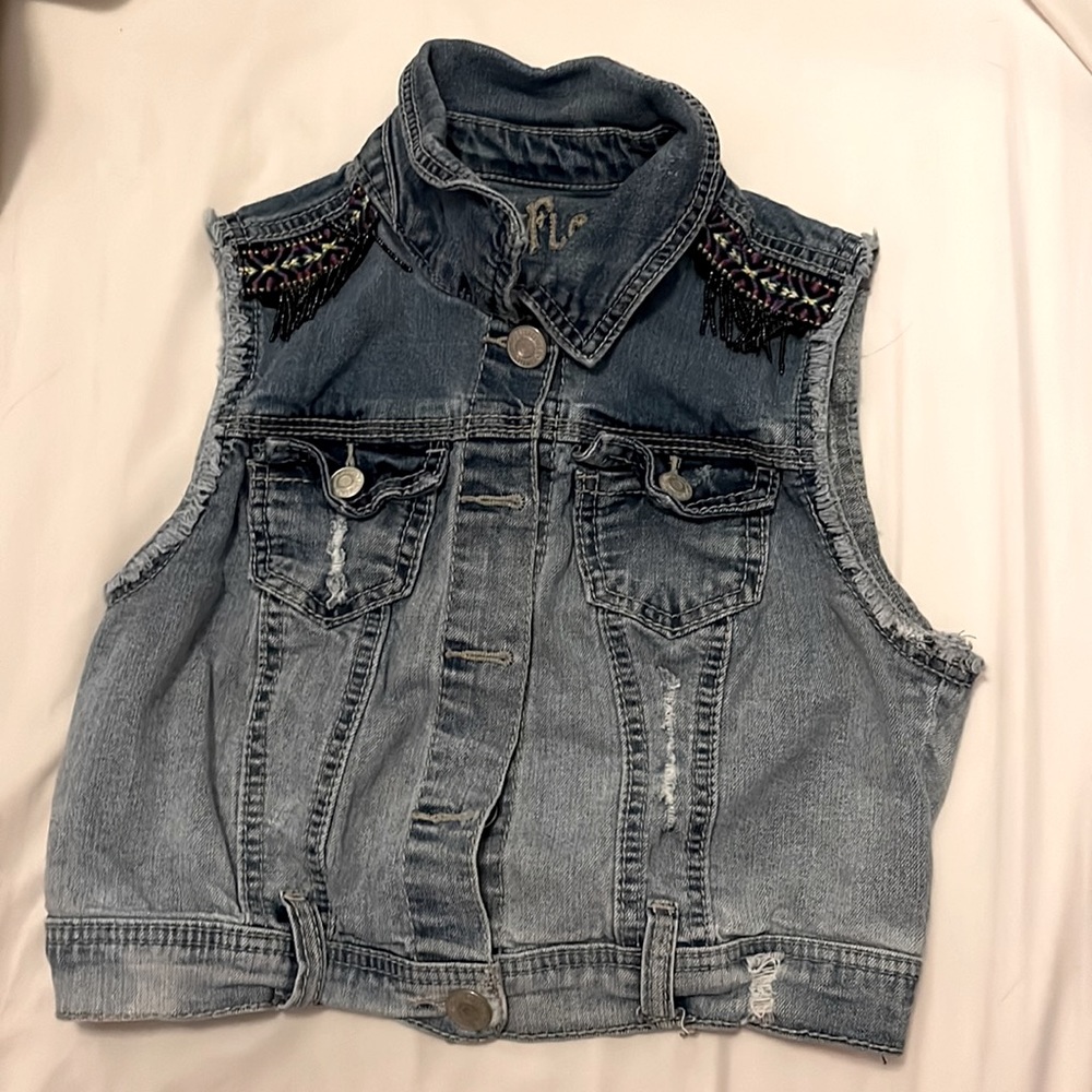 Denim button up vest with cute purple ruffles on the shoulders.